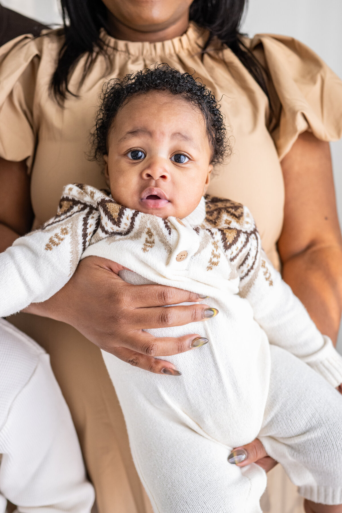 Close up of a baby in her mothers arms and looking at the camera