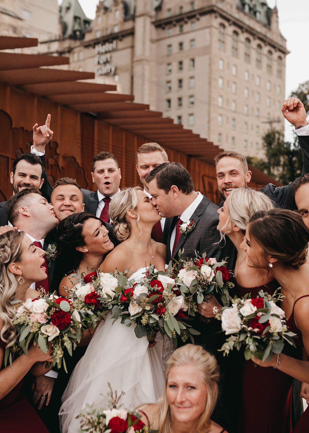 bride and groom kissing surrounded by wedding party