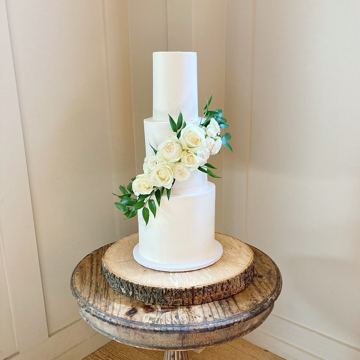 Simple white wedding cake with cascade of white roses