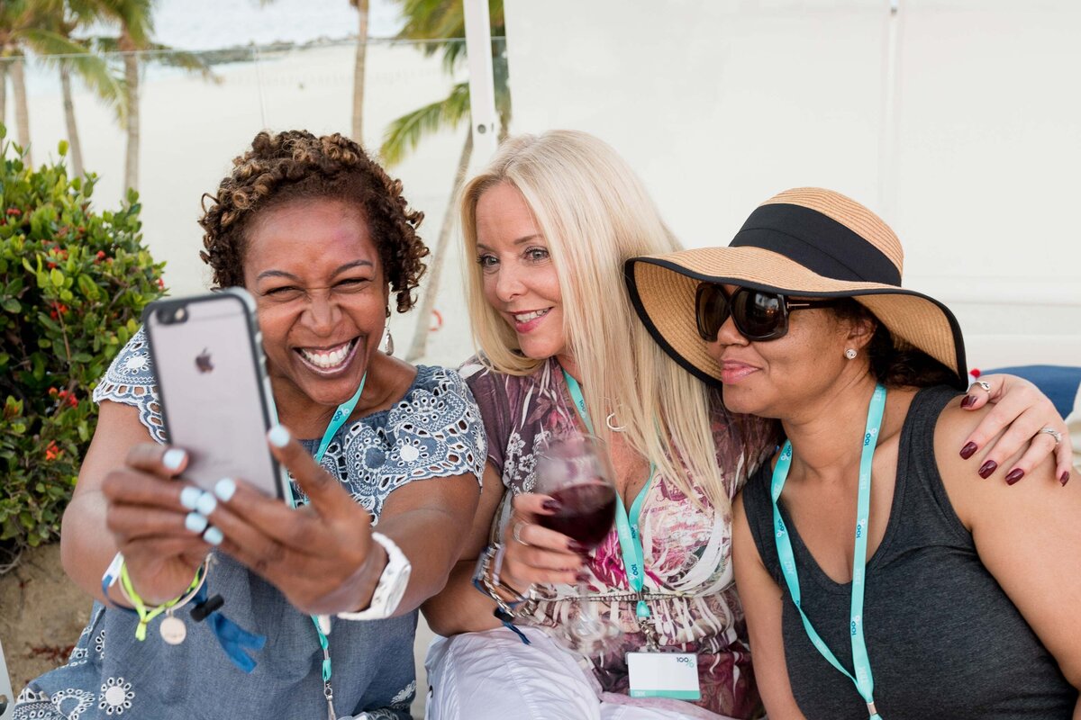 Three women sit and take selfie at their corporate event on Hawaii
