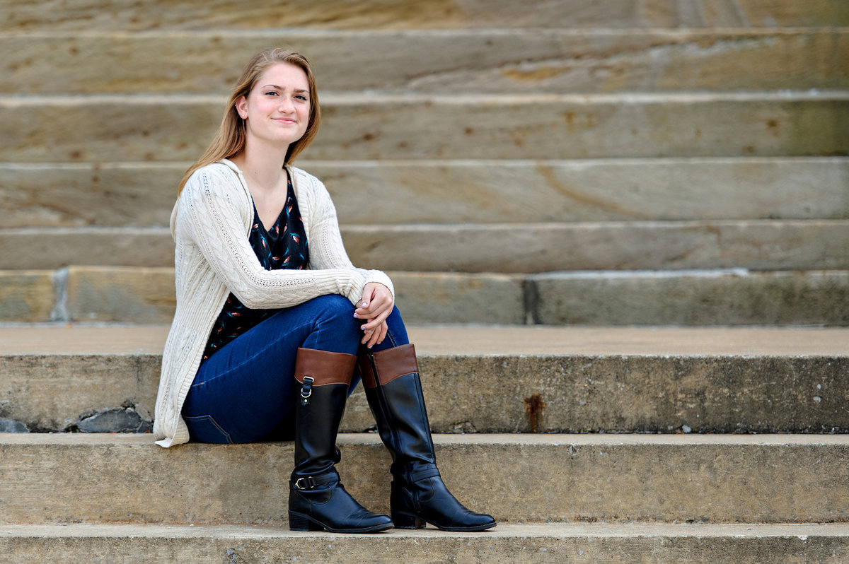 A young college student sits on the steps of her alma mater.