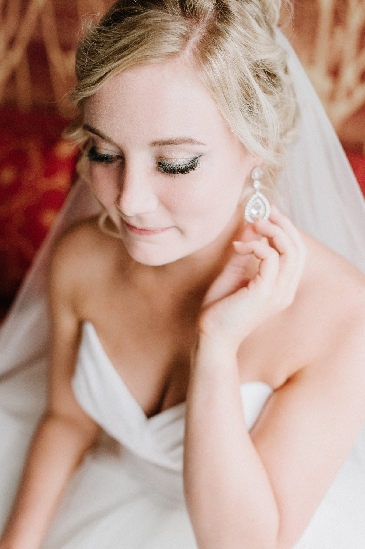 bride wearing strapless dress sitting on couch touching earring