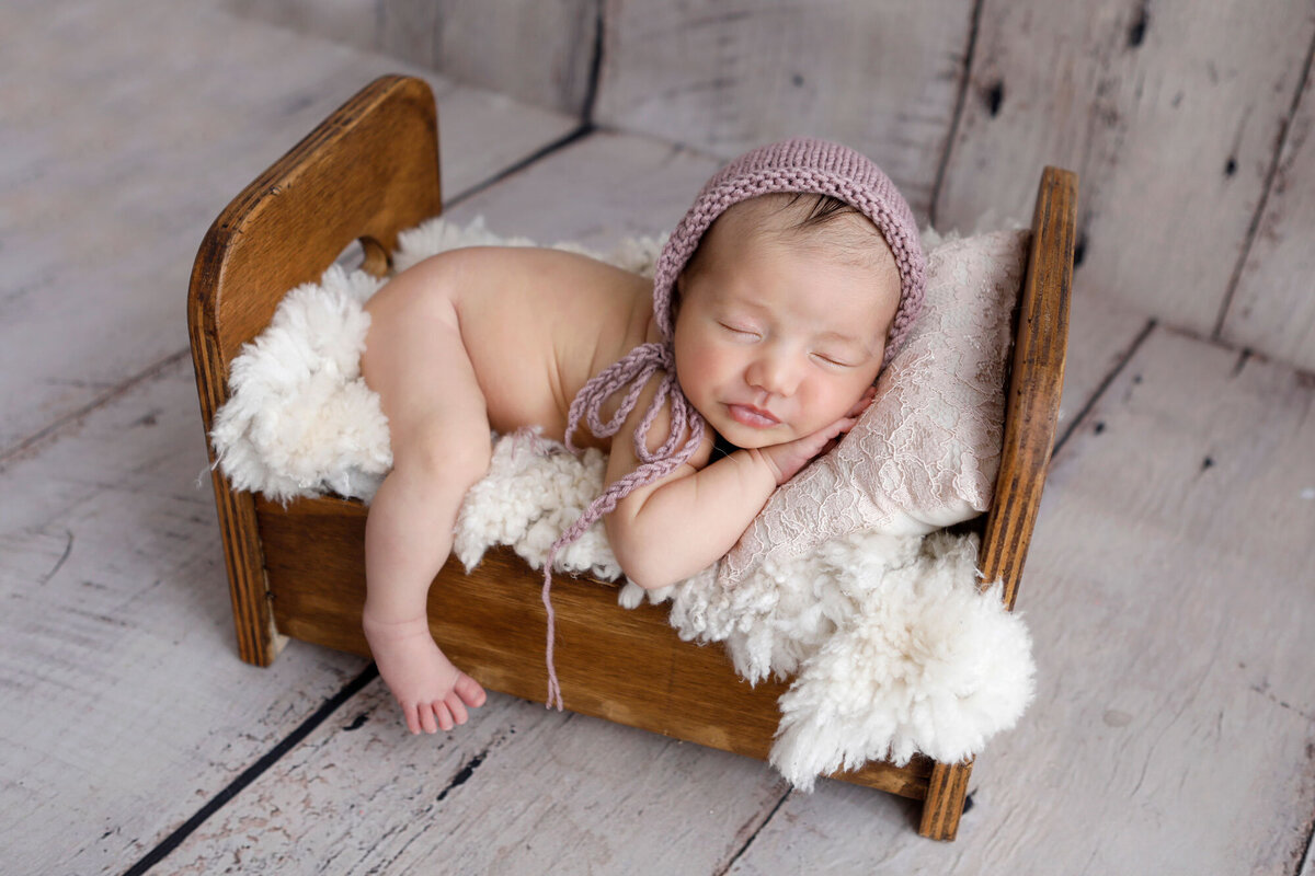 newborn-photography-done-in-Burlington-studio-with-baby-sleeping-in-a-bed-prop