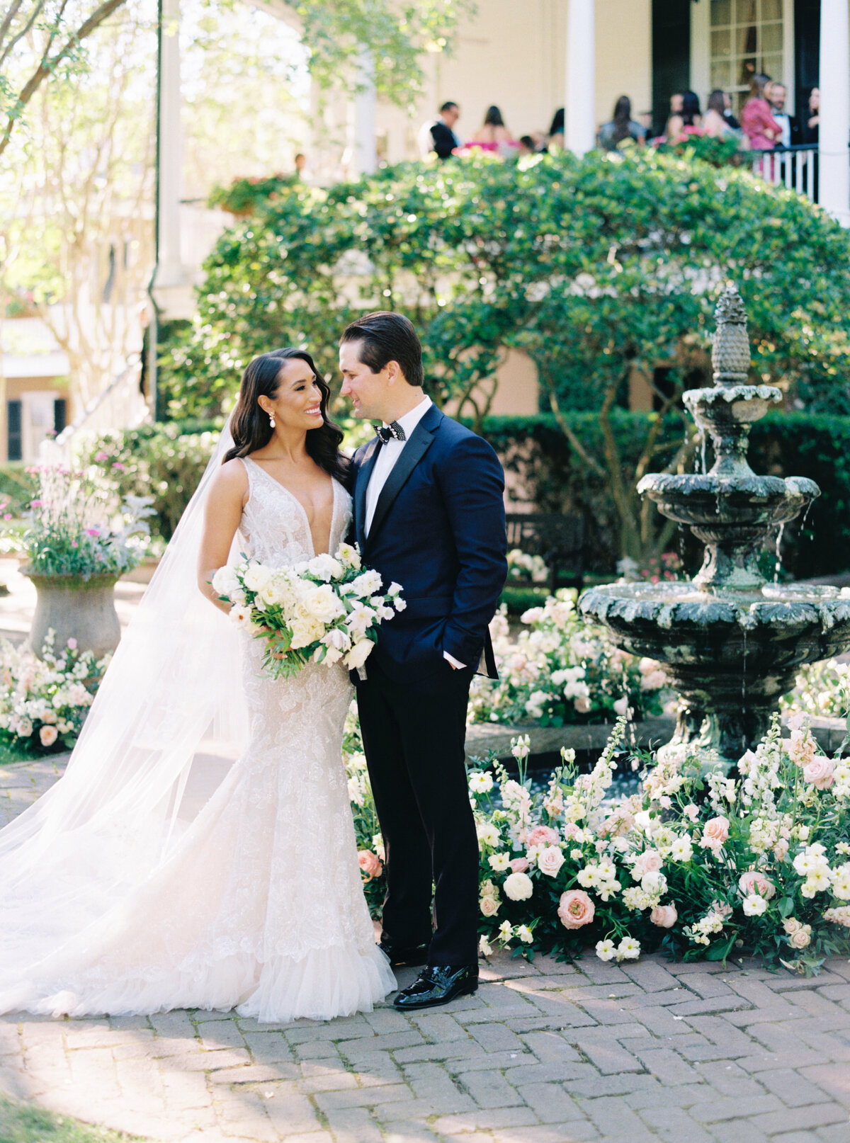 Dark haired bride and groom portrait in front of flower lined fountain at Thomas Bennett House spring wedding.