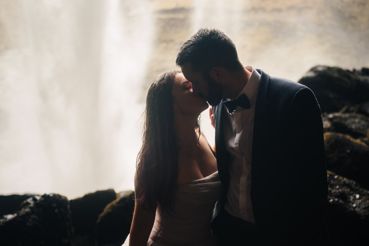 This couple shares a tender kiss inside the enchanting Kvernufoss waterfall cave, creating a magical moment surrounded by the beauty of Iceland's natural wonders.