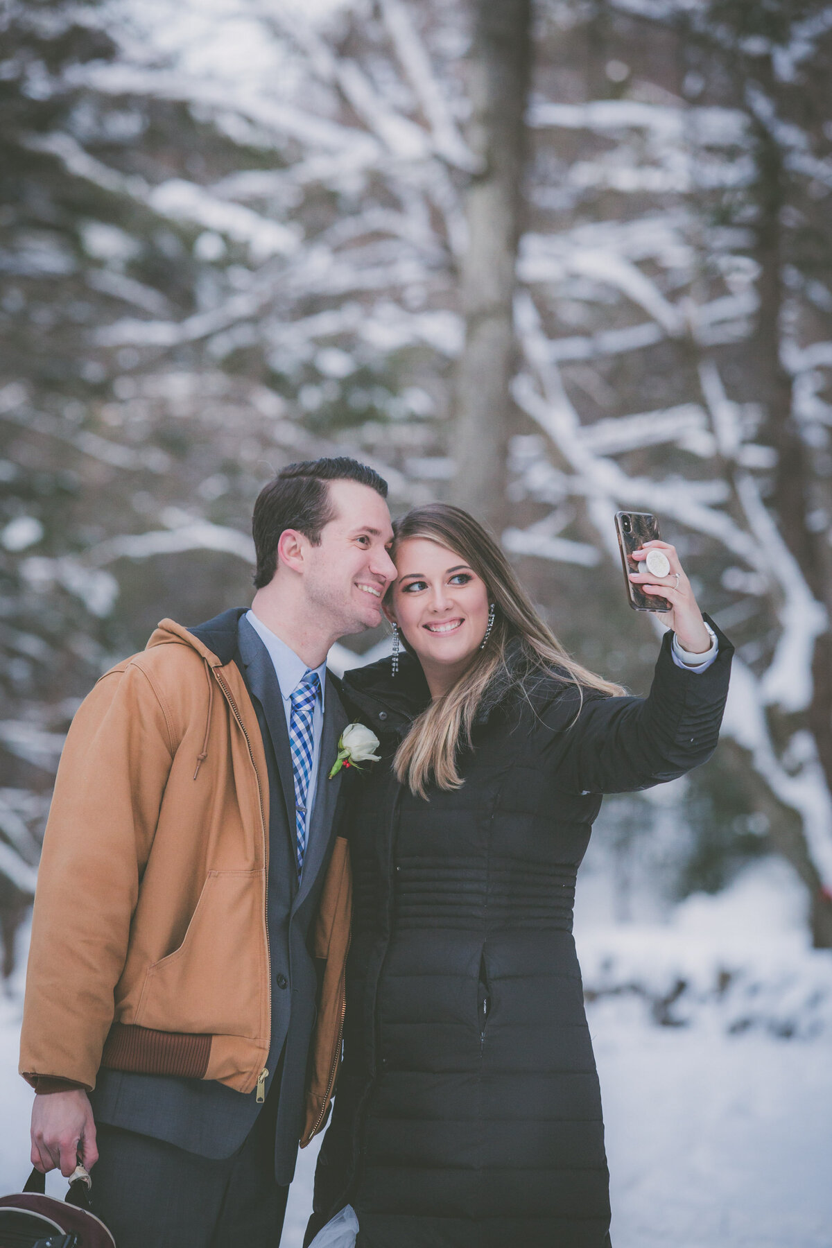 Couple pauses to take a selfie during winter hiking elopement.