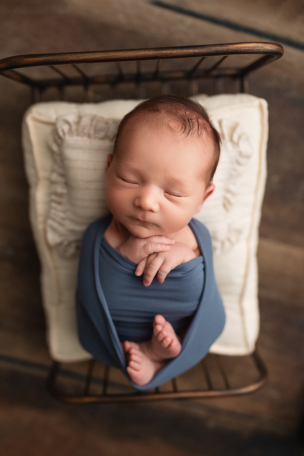 Little boy wrapped in a slate blue wrap during his newborn photography session.