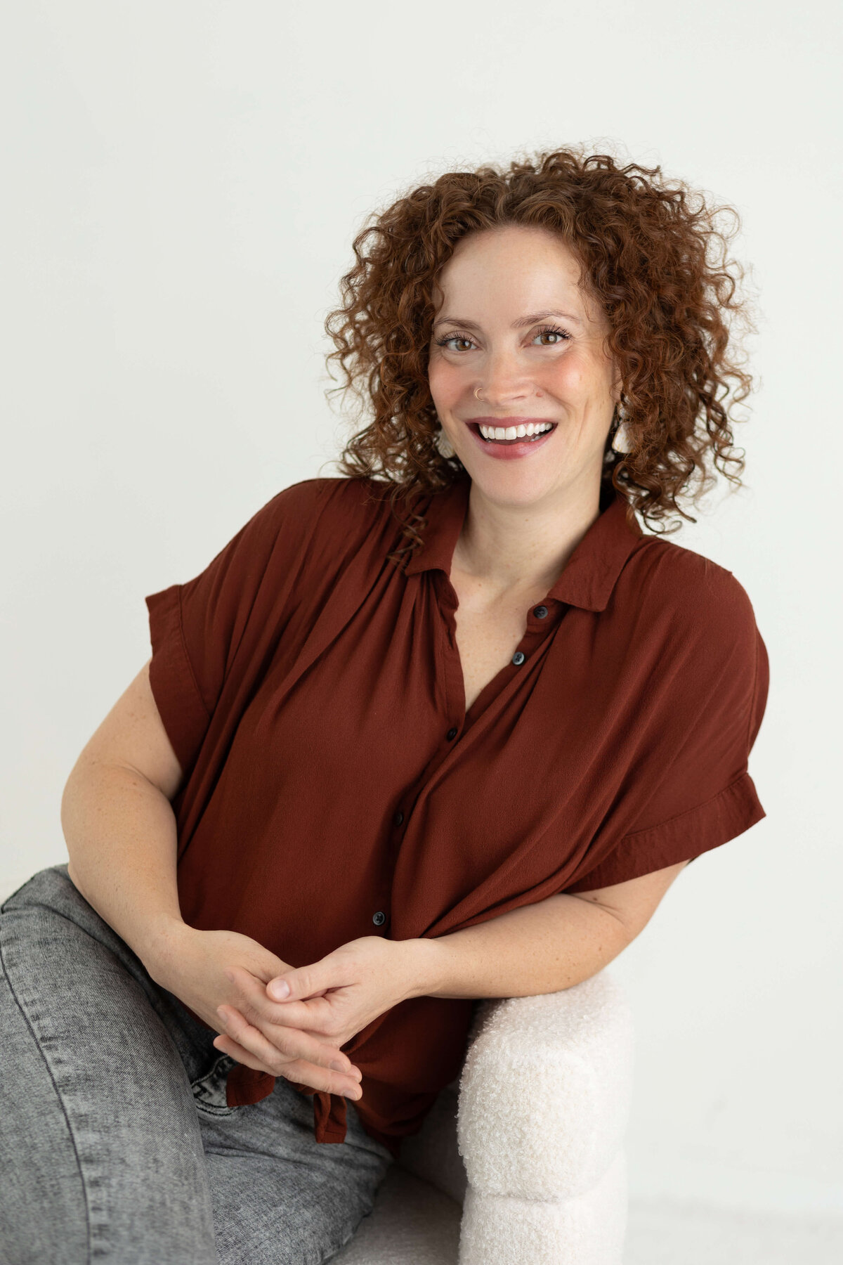 woman with curly hair sitting on a chair smiling
