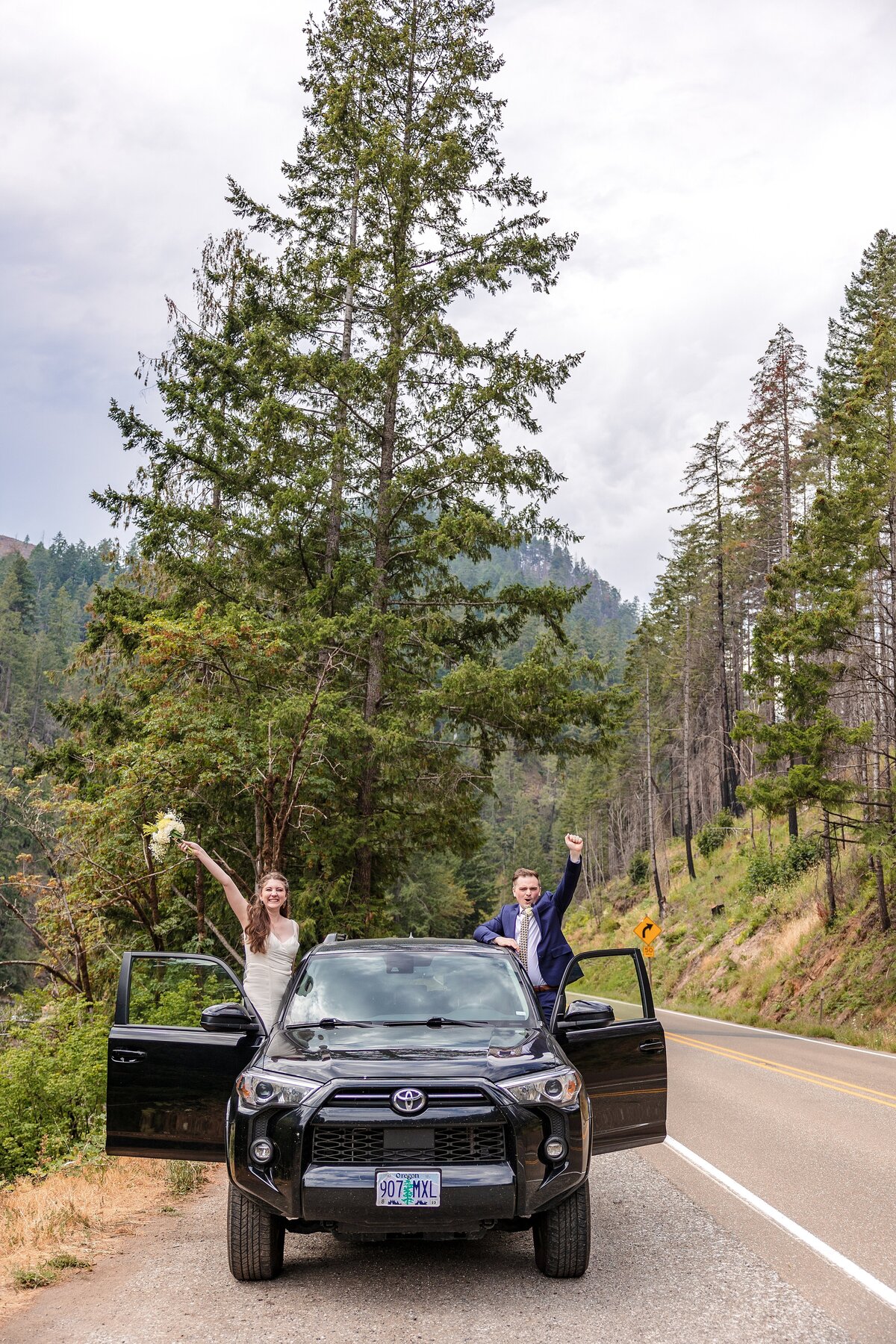 Fun couple hanging out vehicle cheering on elopement day