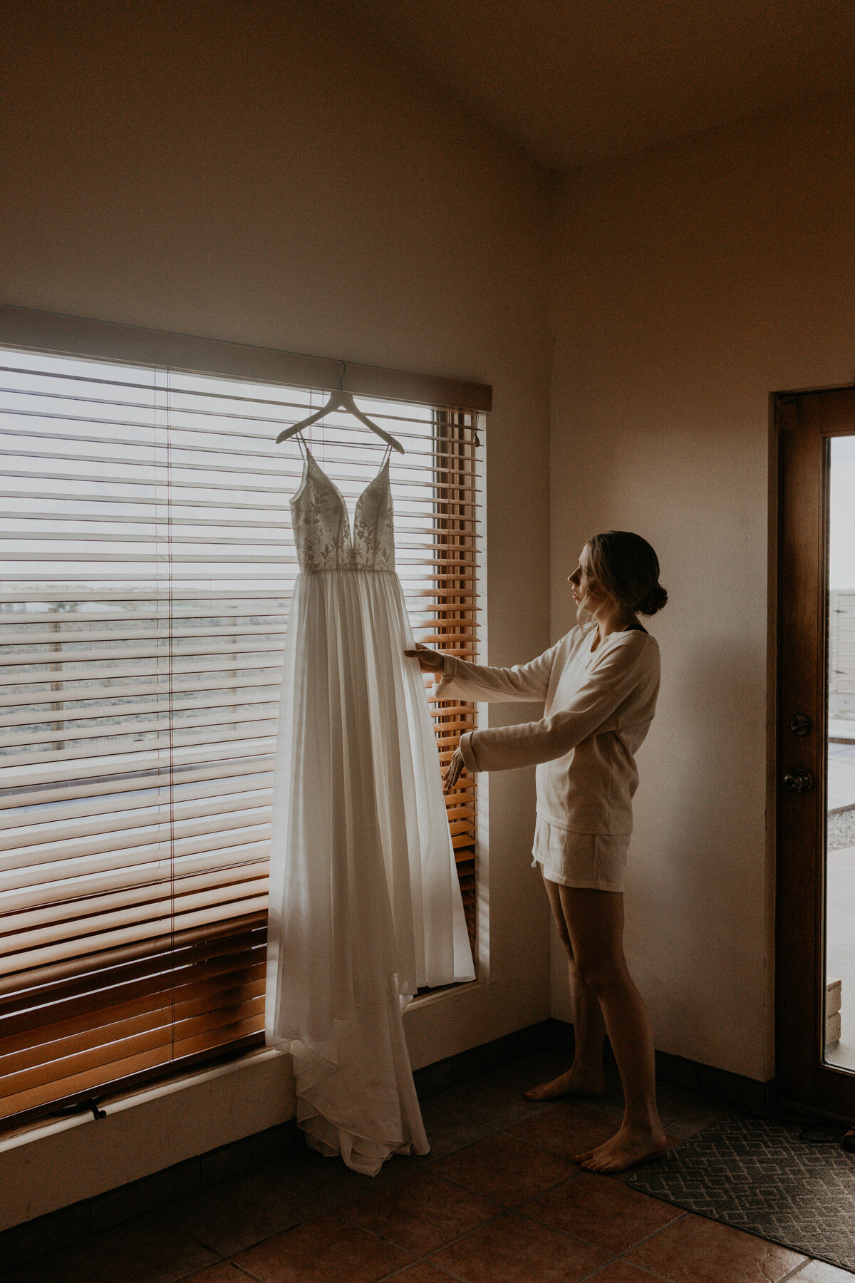 bride looking at her hanging wedding gown before the ceremony
