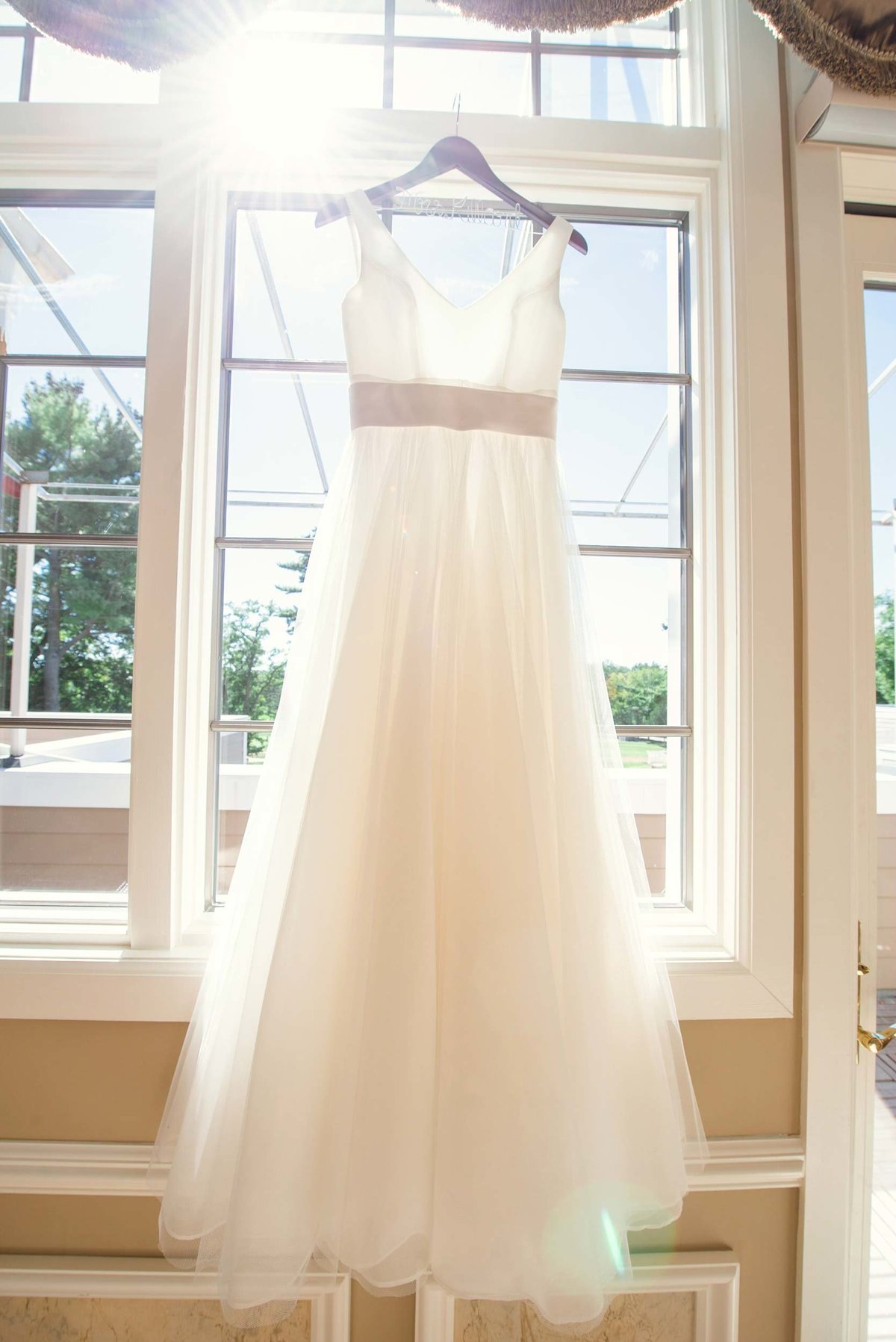 Bride's dress in window with light shining from behind at Stonebridge Country Club