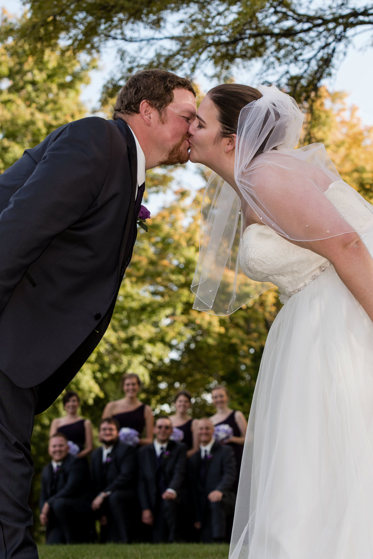kiss with bridal party in background