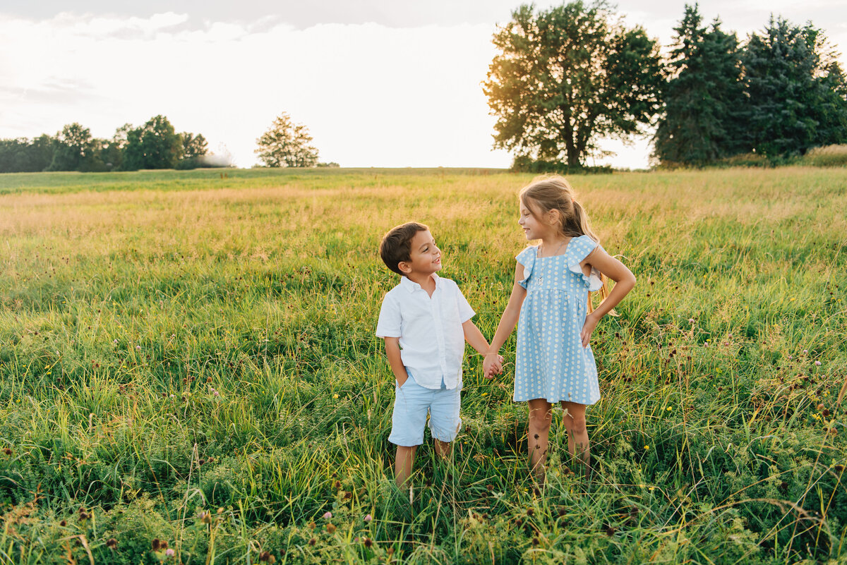 Brother and sister smiling at each other in a field