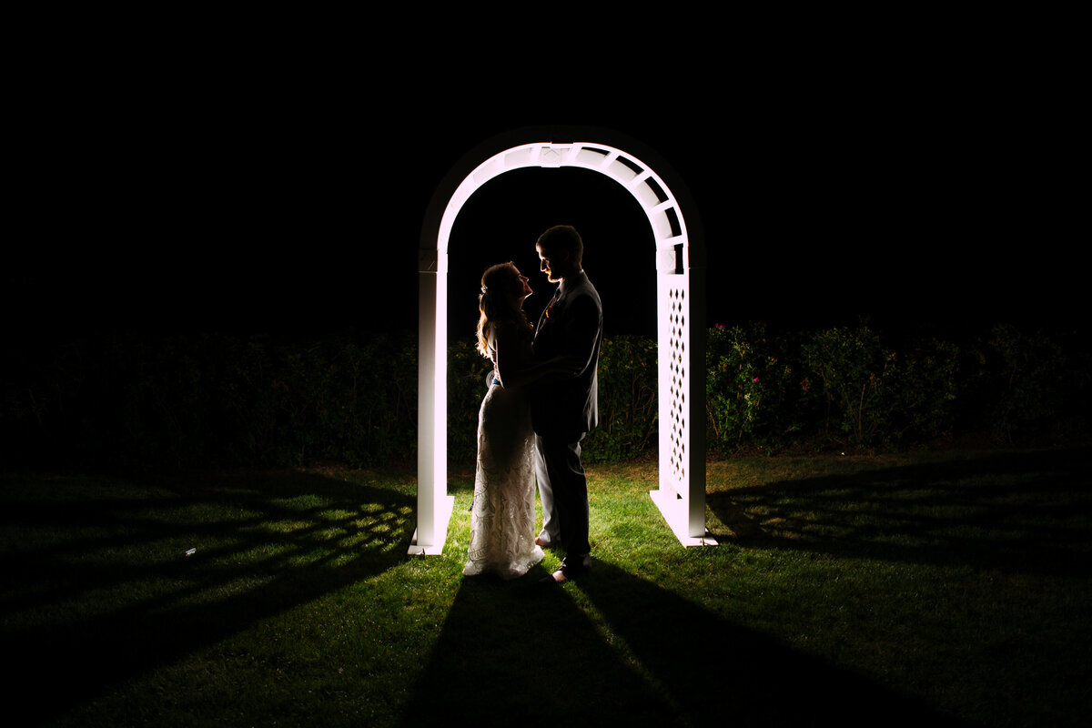 Silhouette night photo of bride and groom under archway at Massachusetts wedding