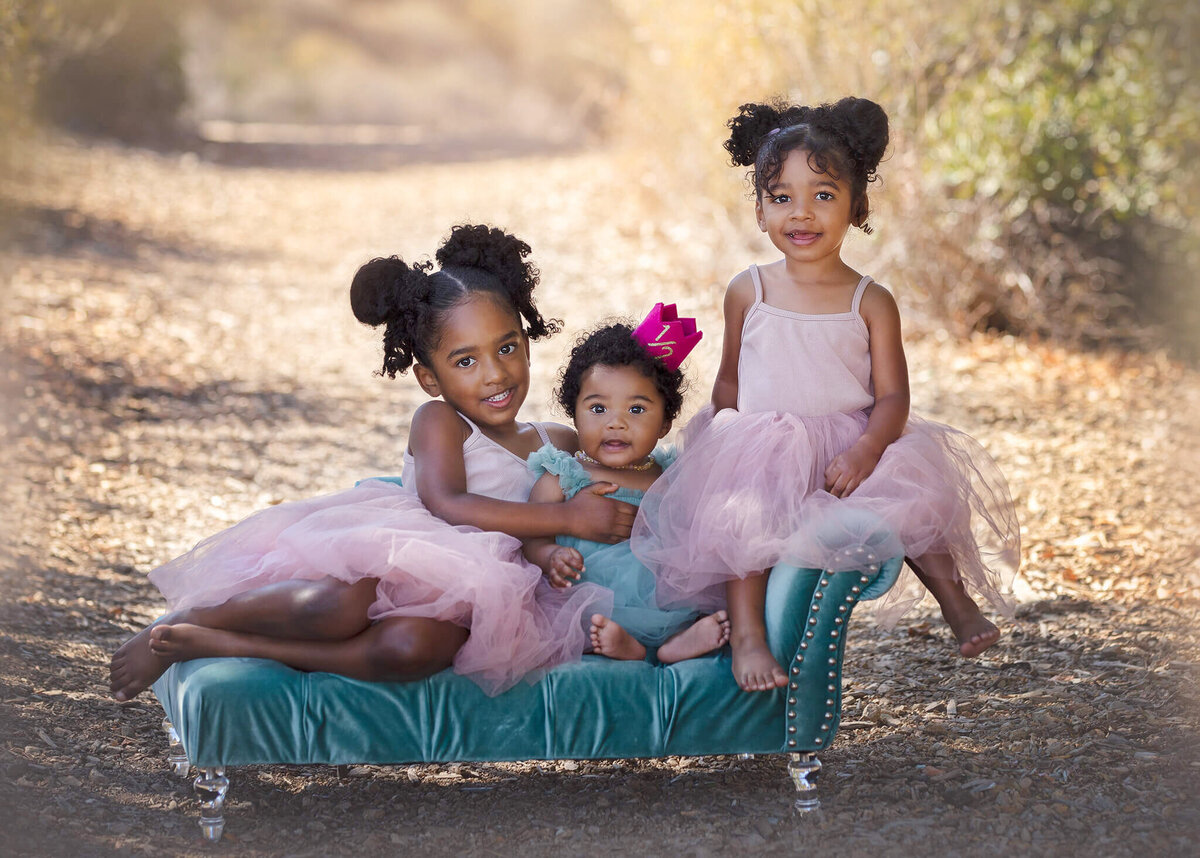 Three sisters sitting on a tiny sofa photographed by Elsie Rose Photography