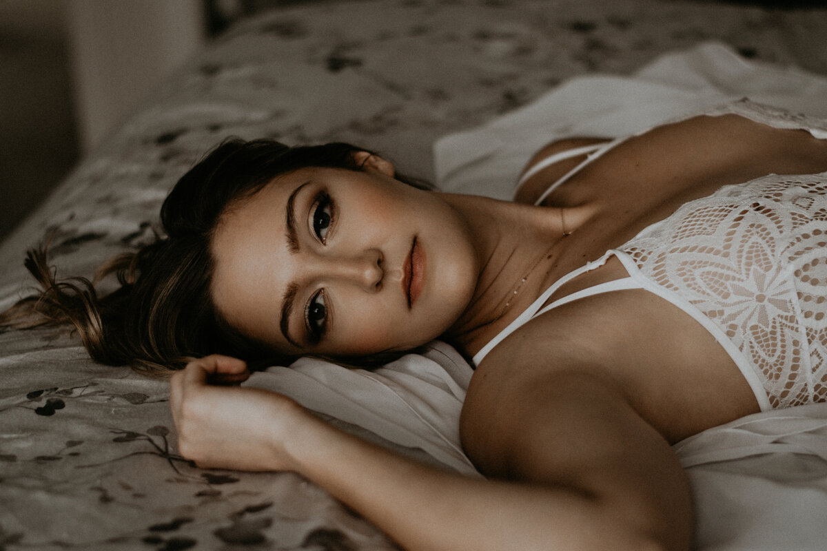 bridal boudoir of a girl laying in a bed looking at the camera