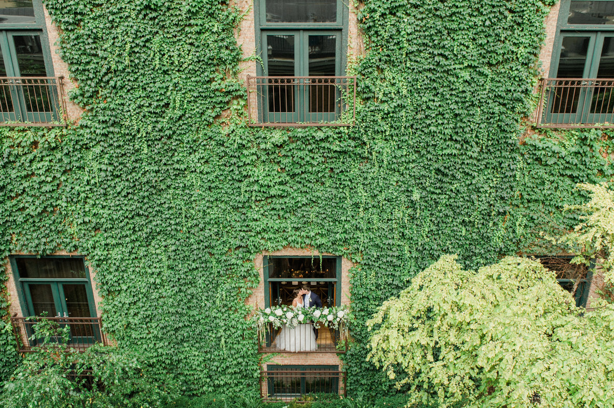 couple kissing on a balcony surrounded by ivy
