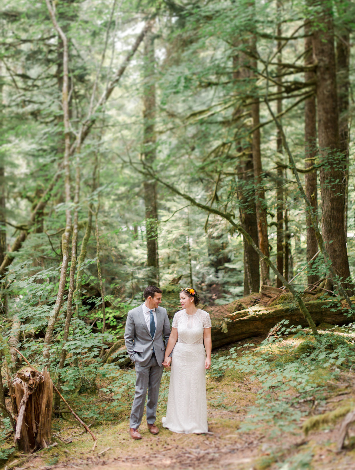 bride and groom stand together in the forest of mount rainier national park
