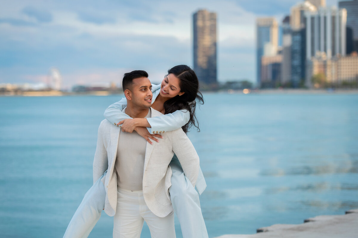 Candid engagement picture at North Avenue beach in Chicago with tall skyscrapers in the background