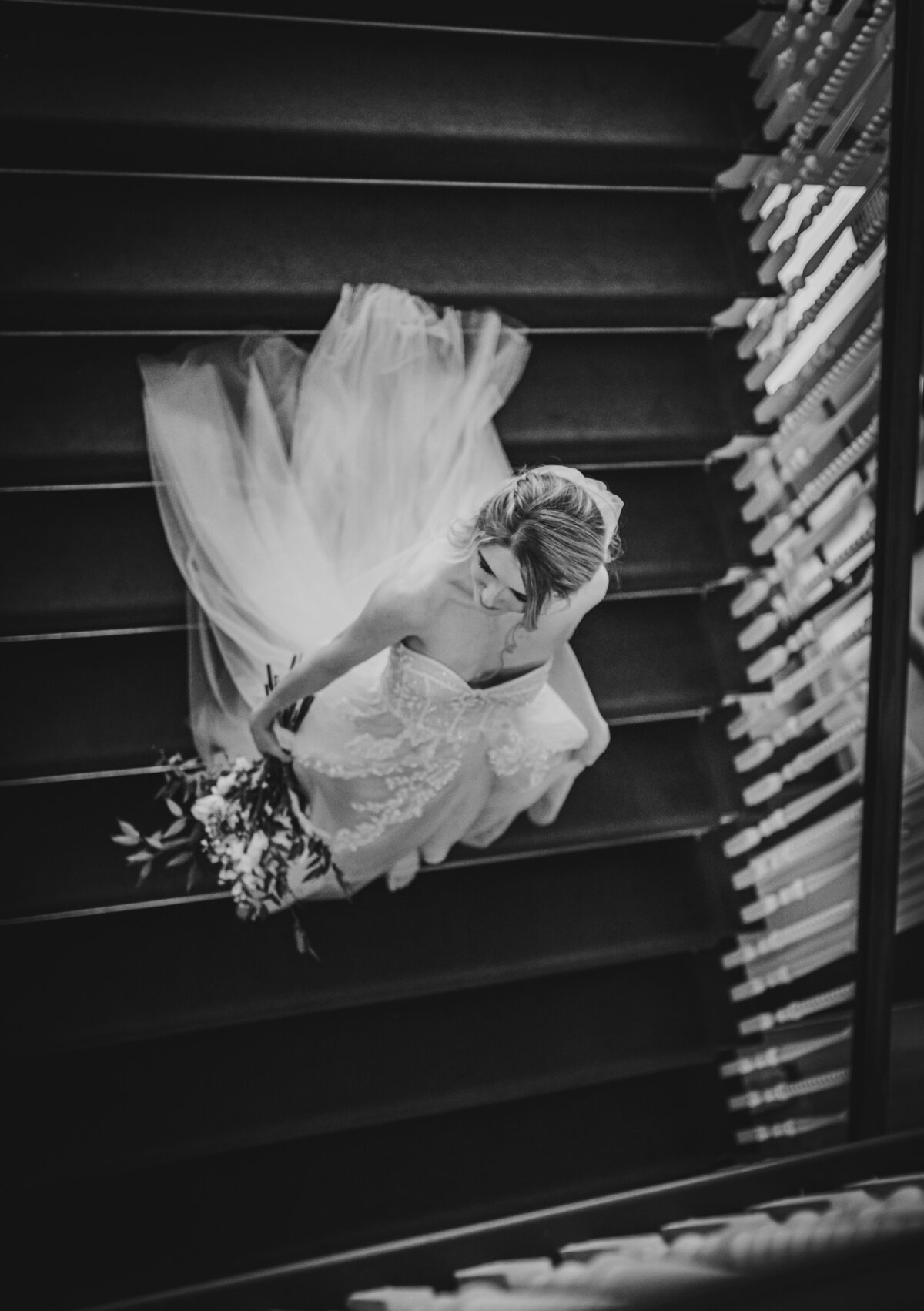 Bride walking down the stairs on her wedding day. Photo in black and white.