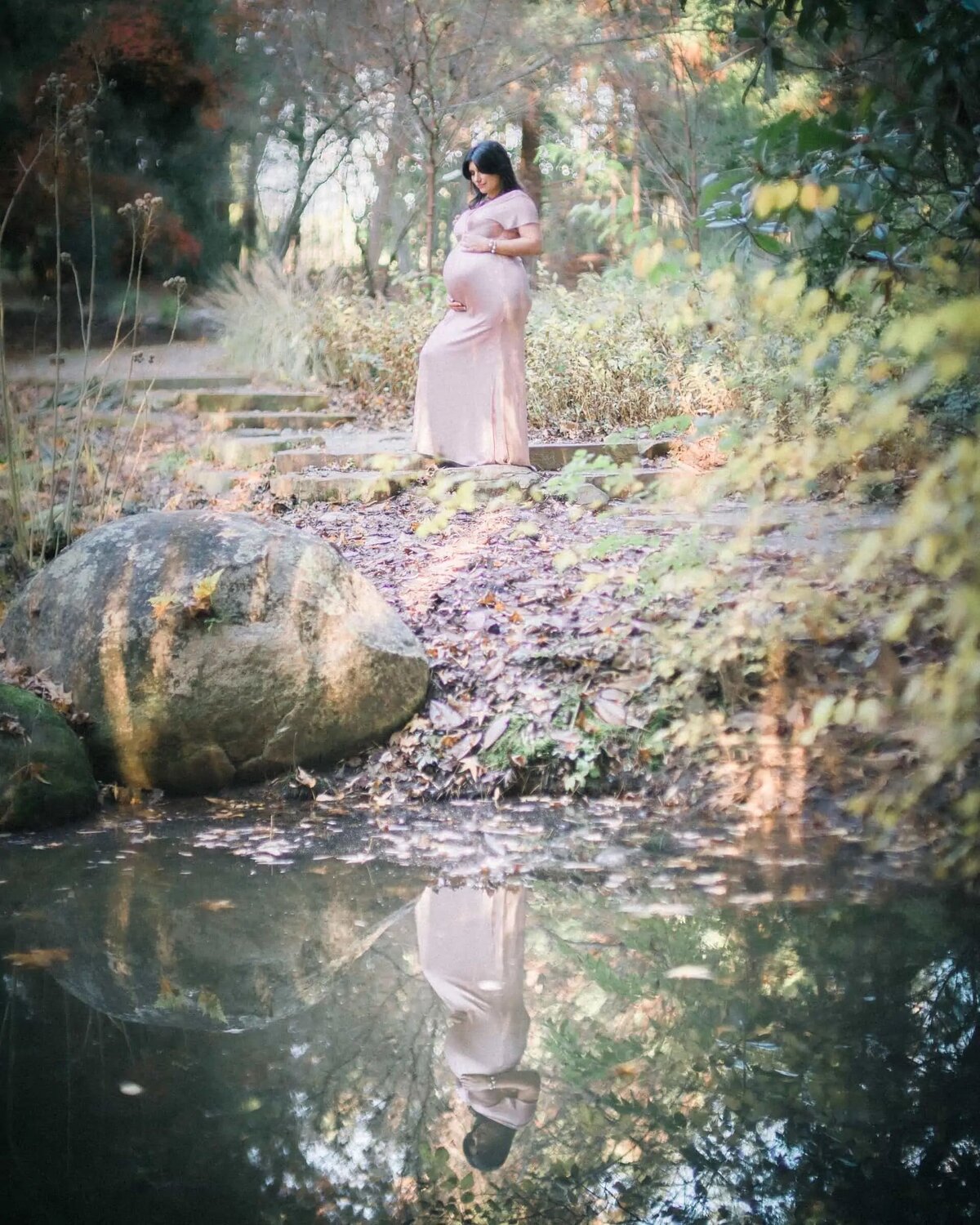 The reflection of a pregnant woman in a small pond.