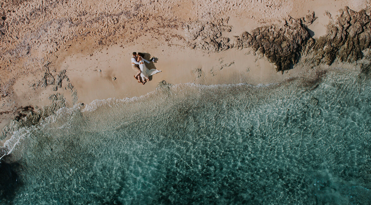 Couple lying on the sand at the waters edgle, taken from above