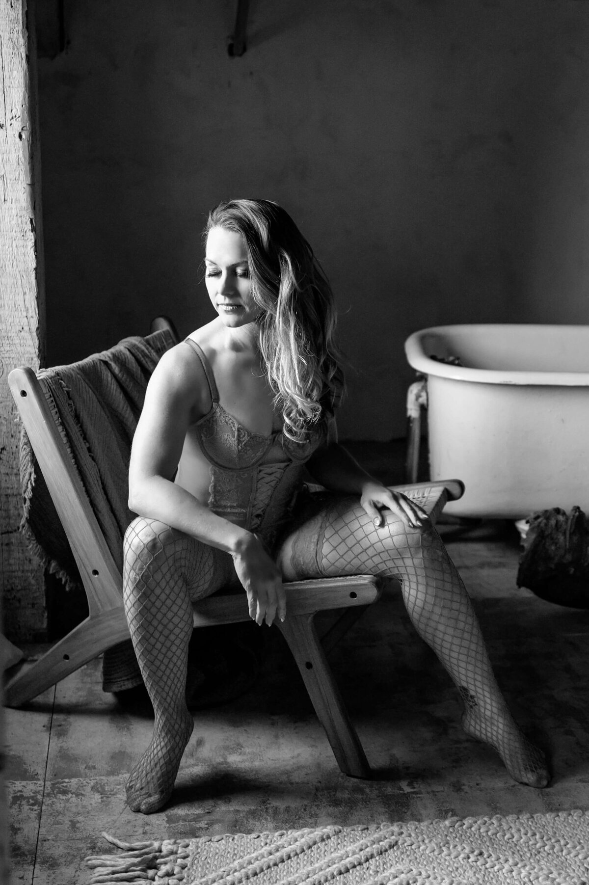 black and white photo of a woman sitting on a chair looking down for her Toronto boudoir photography session