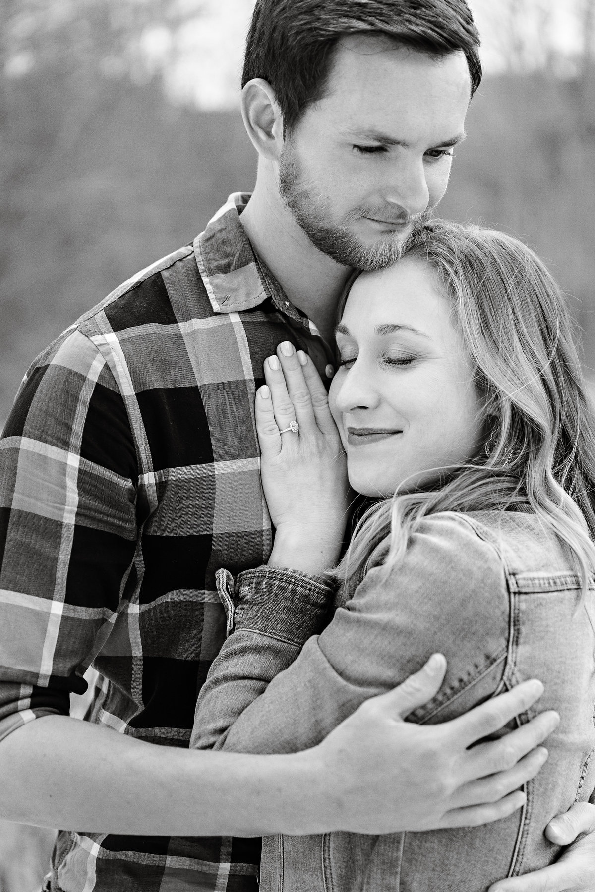 A black and white photo of a young engaged couple embracing sweetly