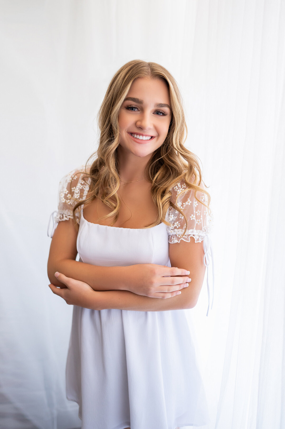 A student from Arrowhead High School poses for her senior pictures in our Downtown Waukesha photo studio wearing all white.