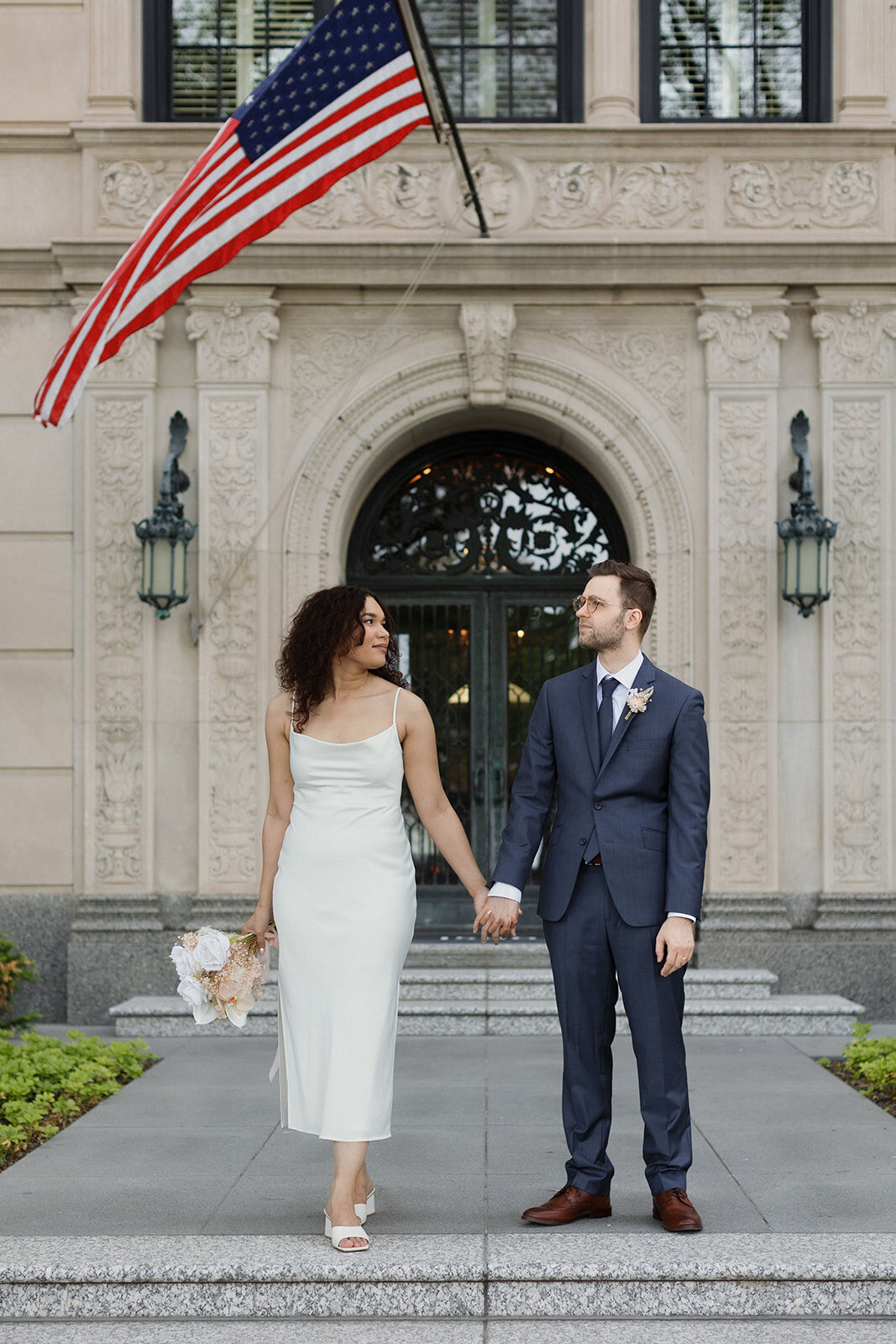 Just Married photo session couple in Gold Coast and stands in front of old building and  holds hands and looks at one another