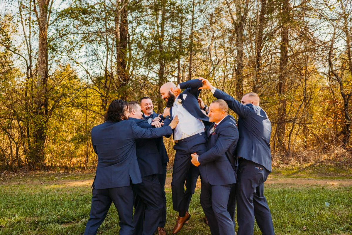 photo of a groom and groomsmen and navy suits horse playing