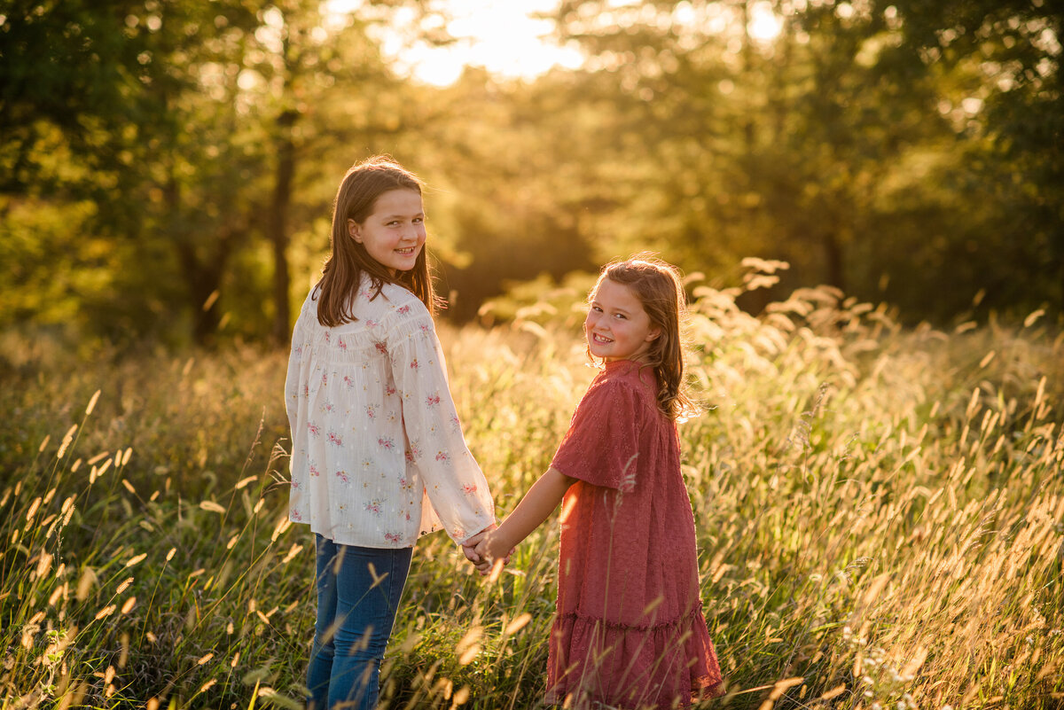 Des-Moines-Iowa-Family-Photographer-Theresa-Schumacher-Photography-Golden-Hour-Grass-Sisters-Looking-Back
