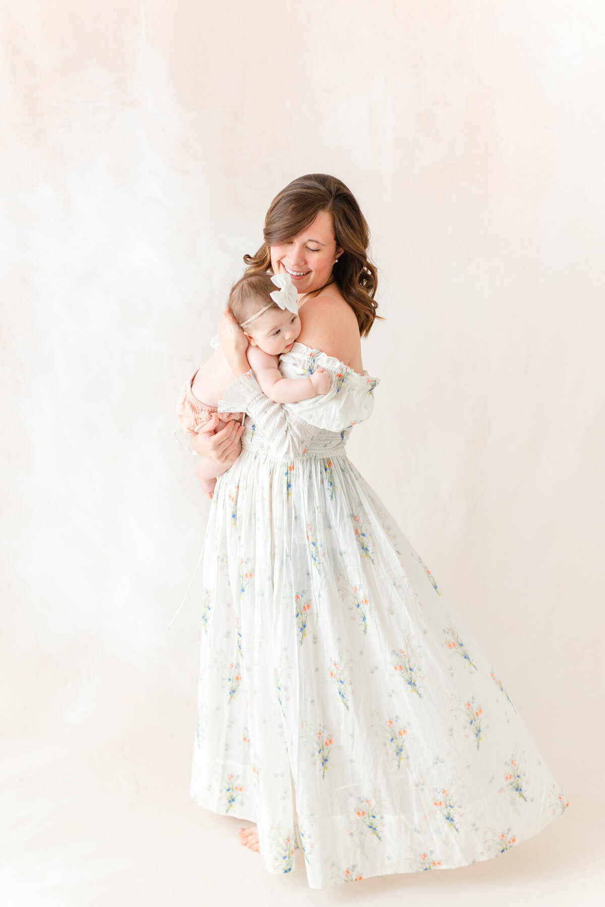 A mother spinning around smiling with her 6 month old baby girl wearing peach bloomers by at a Northern Virginia Family Photography photo session