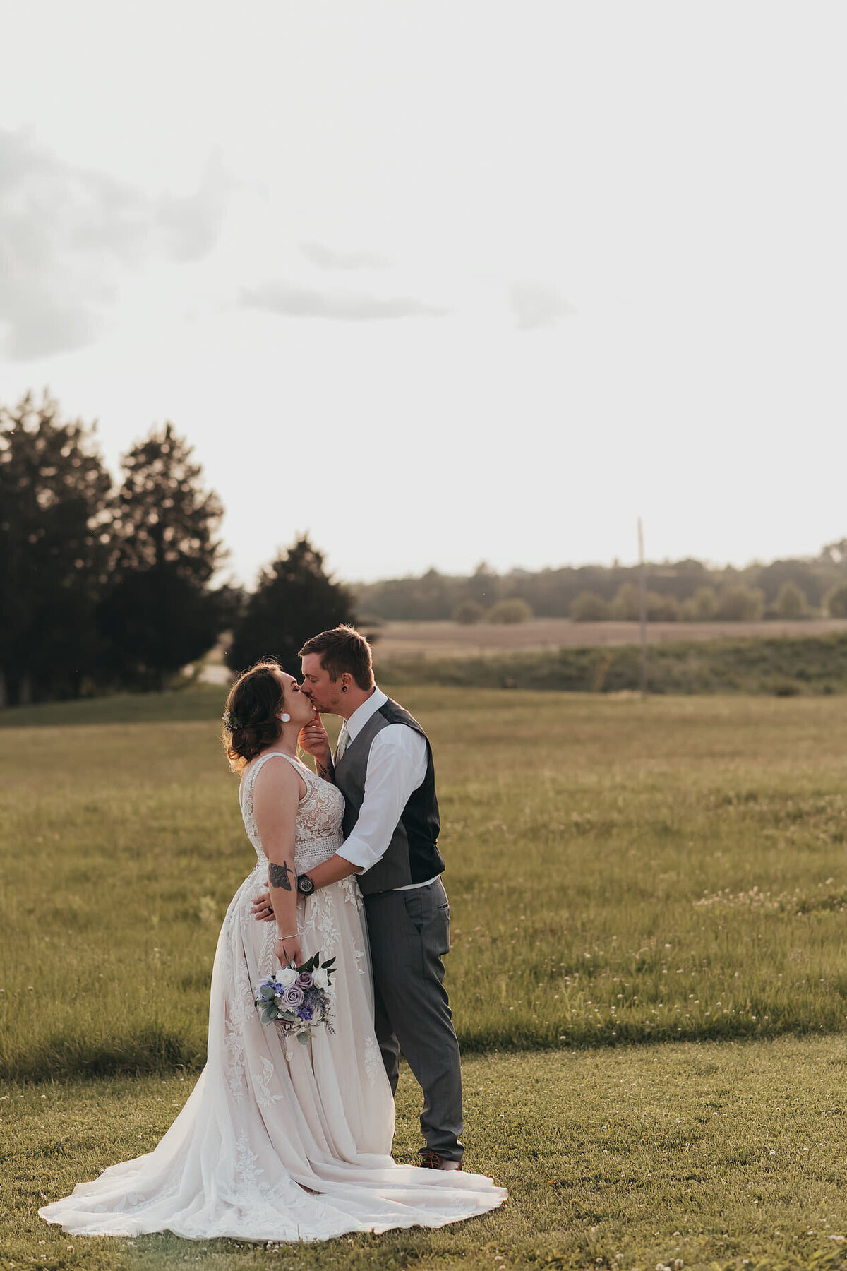 bride and groom kissing in a large field