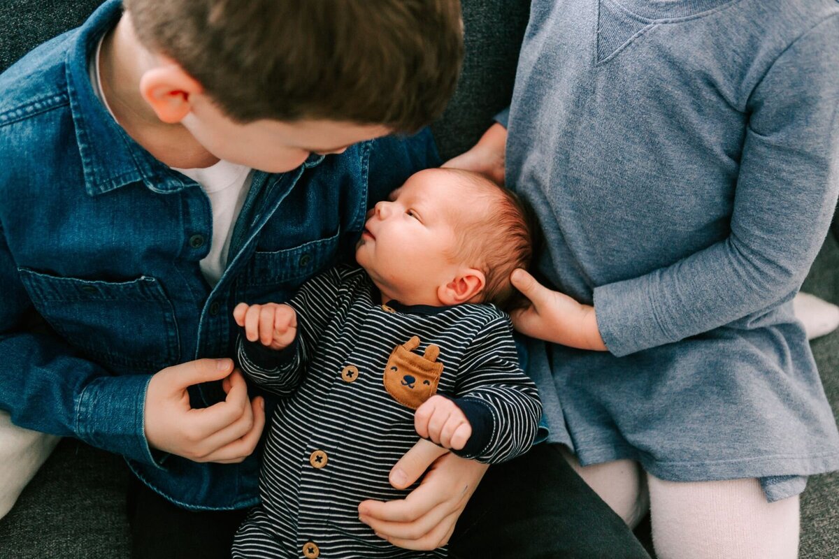 Brother and sister hold new their new baby brother