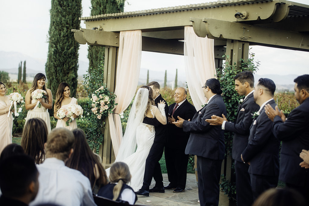 Wedding Photograph Of Visitors Clapping Their Hands To Bride And Groom Kissing Los Angeles