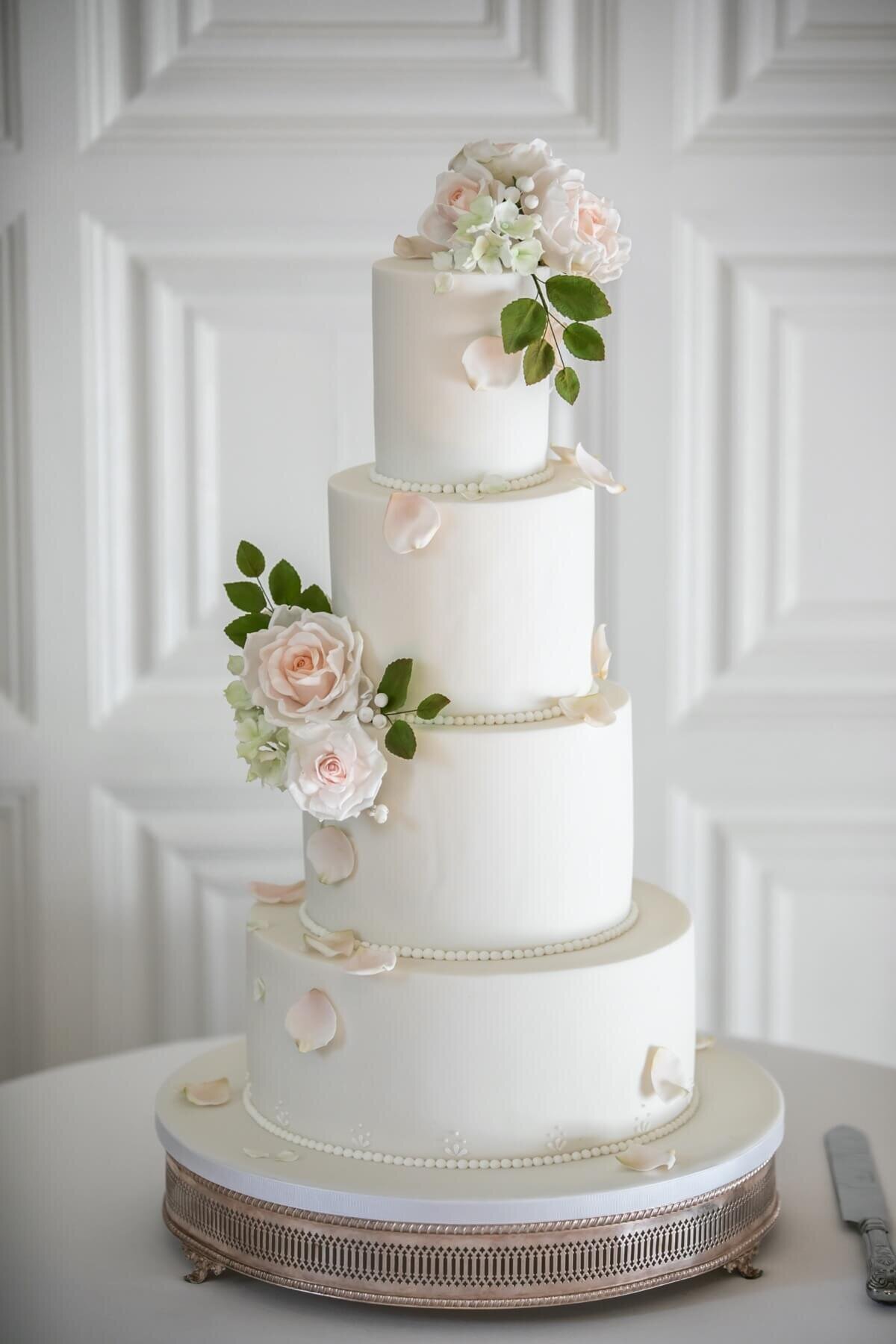 White wedding cake with white sugar flowers, green sugar flower foliage