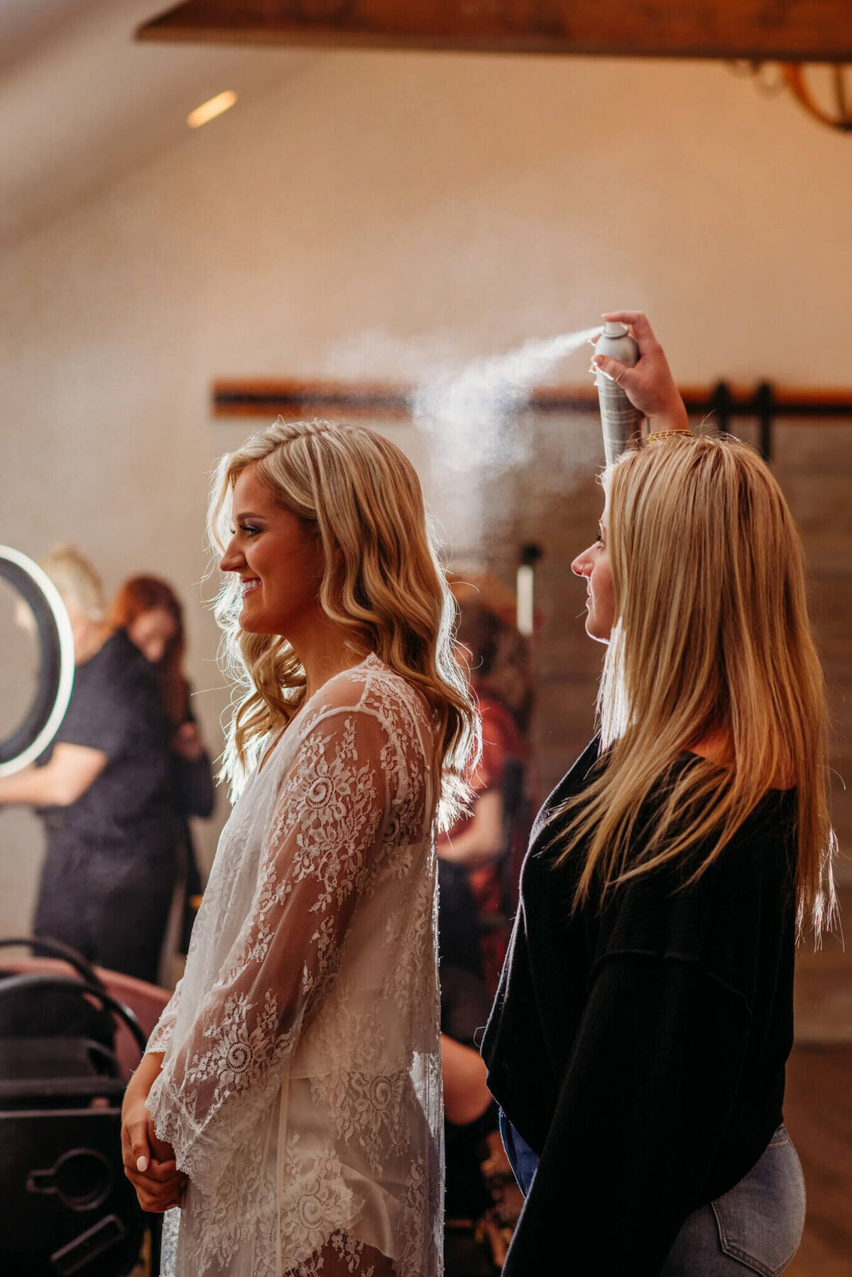 photo of a hair stylist spraying hairspray on a bride