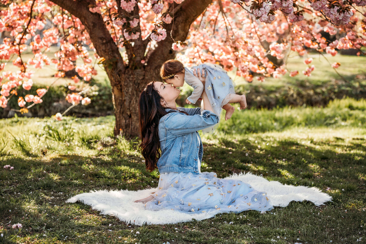 mommy kissing and holding her toddler up in the air in she spring at a mommy and me session