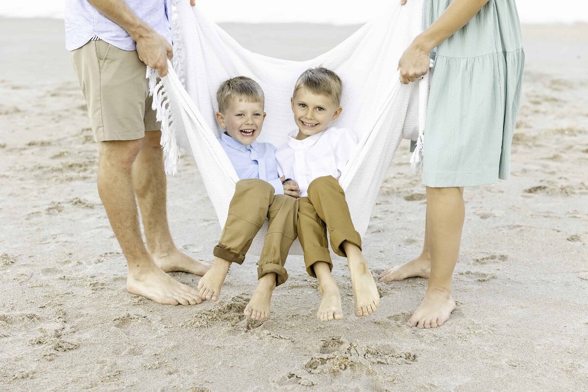 Boys swing in a blanket at the beach