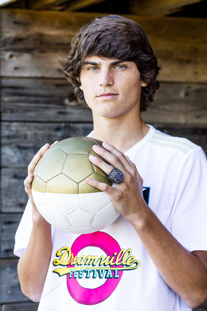 Senior class portrait of a soccer player holding a soccer ball in a park in Wake Forest, NC.