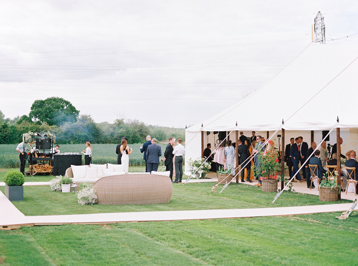 luxury white wedding marquee with outdoor grill and guests enjoying themselves