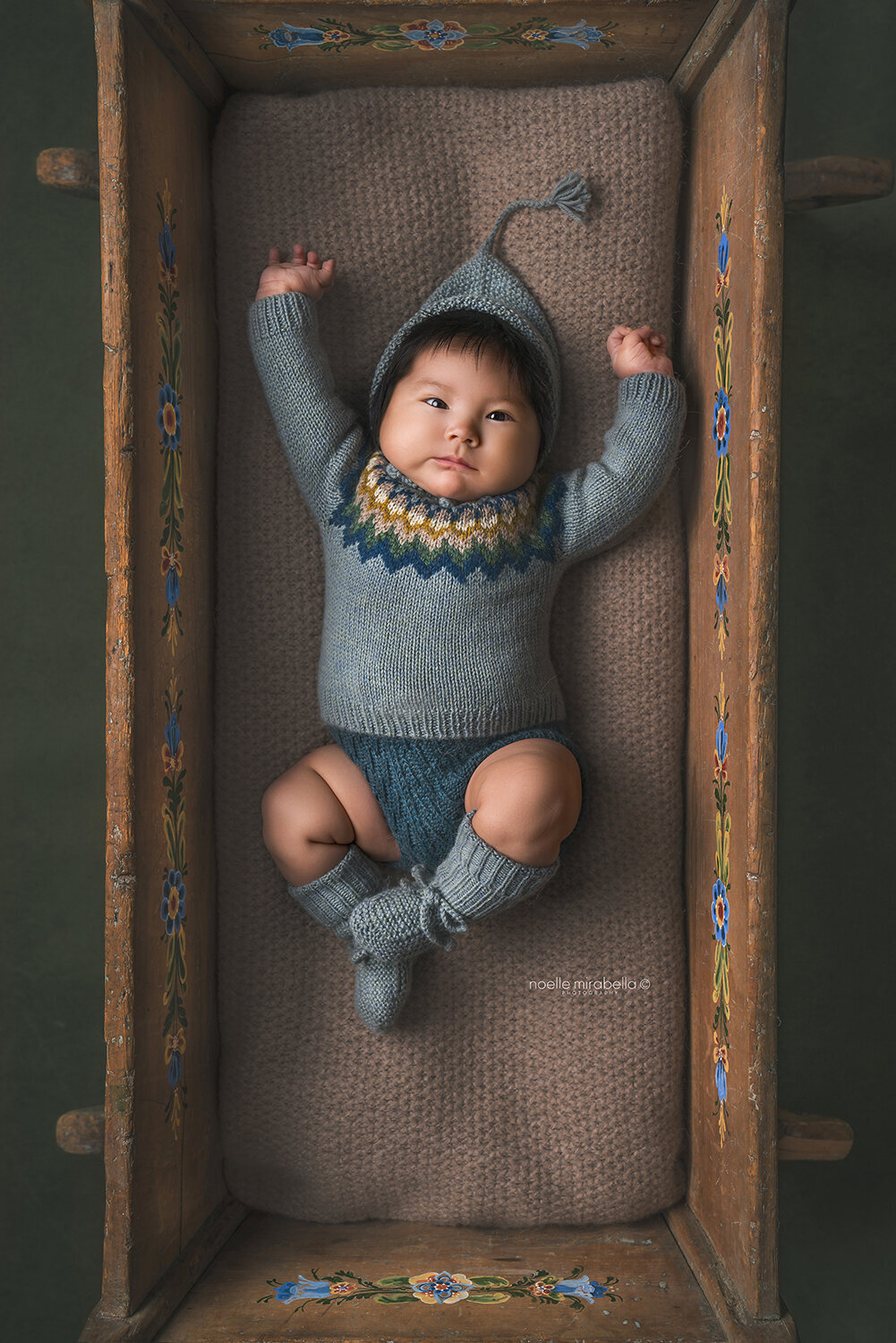Baby stretching in a wooden cradle.