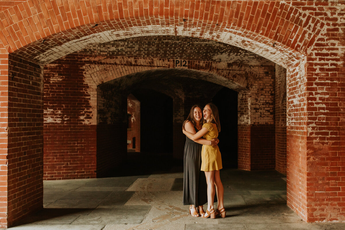 Lifestyle photo os teenage sisters hugging and smiling at Fort Point in San Francisco