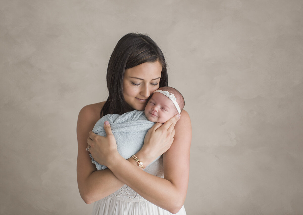 a young women with her newborn and a grey backdrop