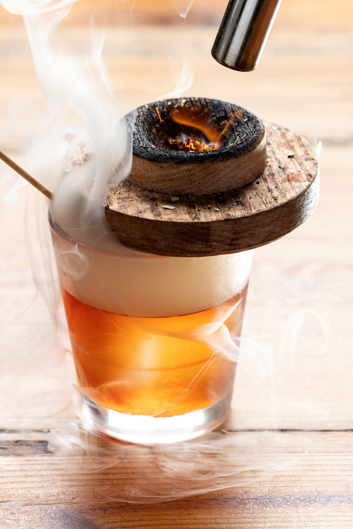 A piece of wood being burned on top of a cocktail