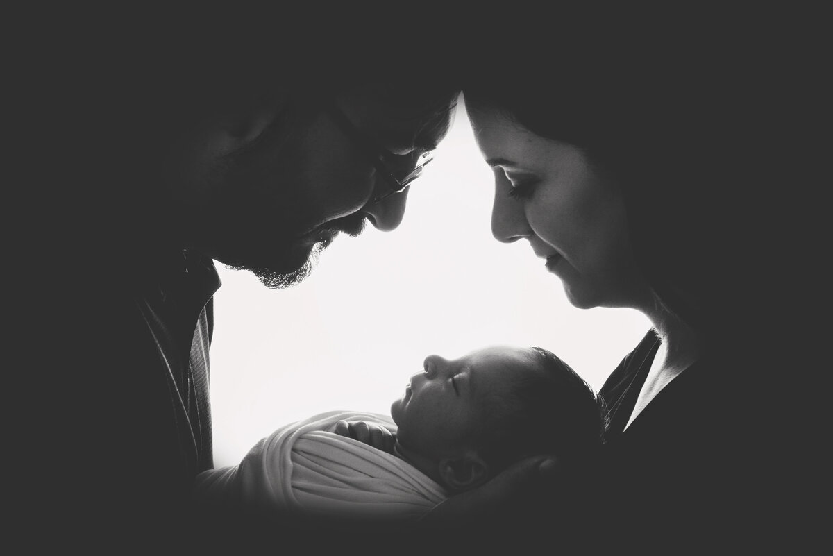 st-louis-newborn-photographer-black-and-white-photo-of-parents-cradling-swaddled-baby