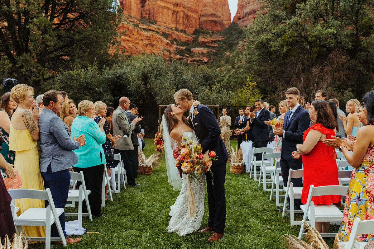 couple stops for a kiss down the isle at enhchantment resort in sedona