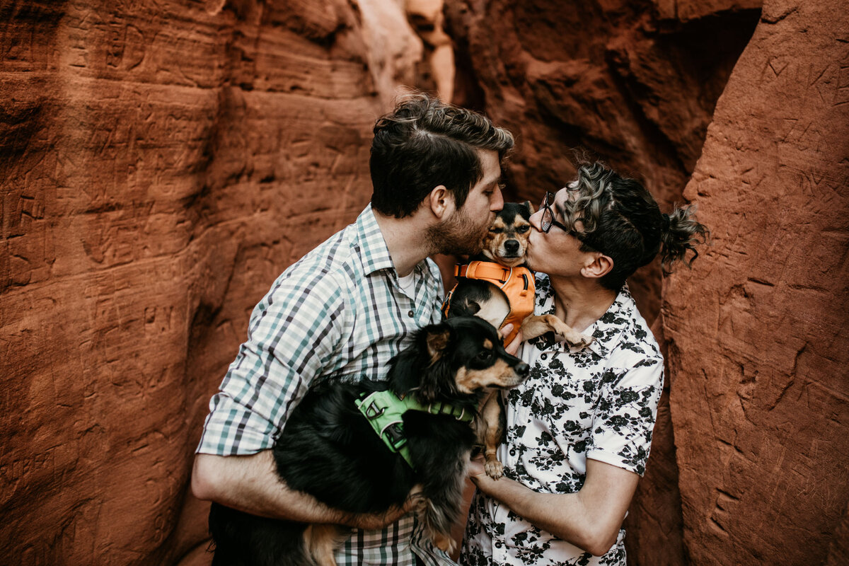 gay couple holding and kissing dogs in canyon