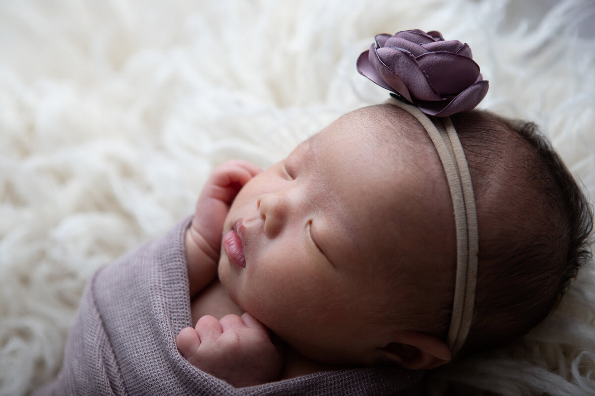 Purple wrapped backlit newborn on a bone flokati
